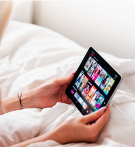 A pair of female hands holding a tablet while viewing social media.